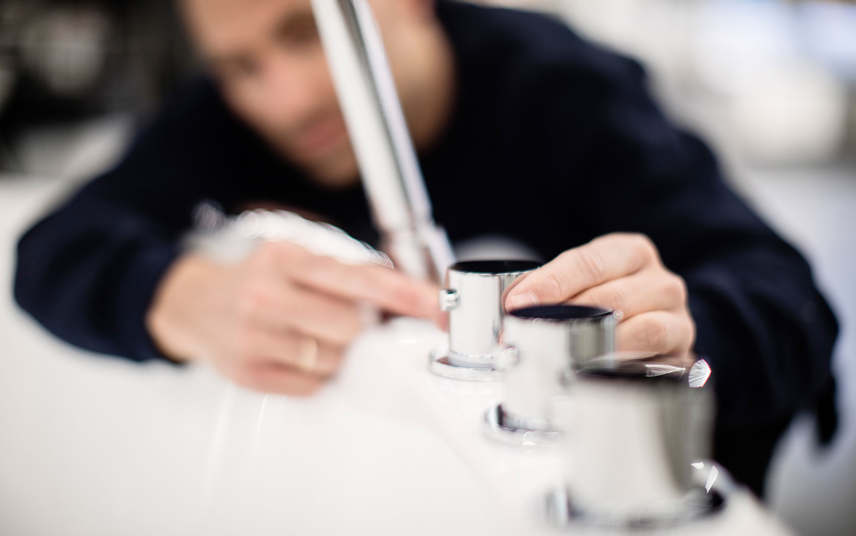 VB Dinas Bygg Rørlegger monterer et kromfarget blandebatteri på en hvit servant på et bad